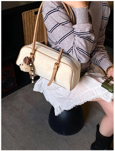 Detail of cream baguette bag with brown leather trim and cute teddy bear charm