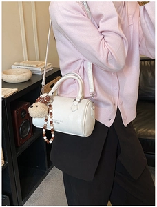 Detail of white Boston bag with bear pendant and beaded charm shown on model