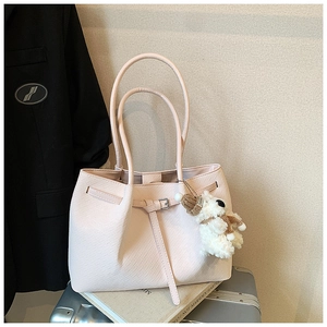 Close-up of pink woven tote bag with a cute bear charm and decorative buckle detail