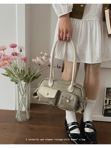 Detail of vintage canvas shoulder bag featuring multiple pockets and top handle
