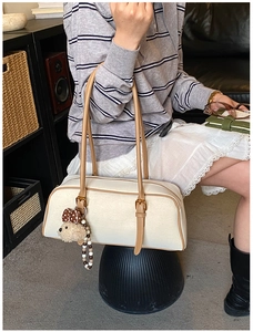 Detail of cream baguette bag with brown contrast trim and cute teddy bear charm