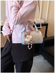 Detail showing shiny silver Boston bag with a cute bear charm and fashion text engraving