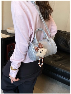 Detail of silver metallic Boston bag with cute teddy bear charm and crossbody strap
