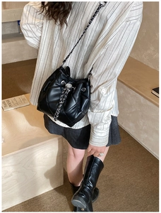 Detailed view of black quilted bucket bag with silver metal drawstring and chain strap