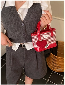 Detail of red gingham plaid bucket bag with plush heart charm and Helahe patch
