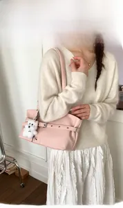 Pink faux leather tote bag with stylish buckle strap detail and a cute puppy plush charm