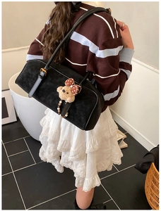 Detail of black Boston shoulder bag with cute brown bear charm on a model