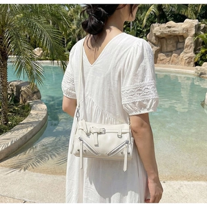 Detail of off-white motorcycle bowling bag with long tassels and silver rivets on shoulder strap