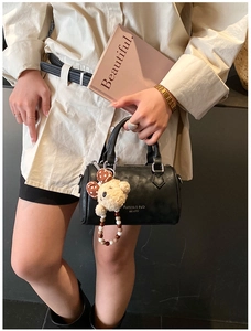 Close-up of black leather Boston bag with teddy bear charm and Fashion & BaG logo