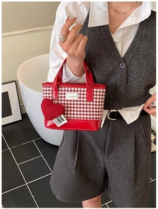 Close-up of a red and white checkered mini bucket bag with a plush heart charm