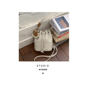 Detail of white lychee leather bucket bag with drawstring closure and horse charm