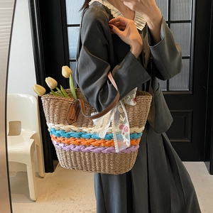 Straw woven tote bag with colorful stripes and floral lace ribbon held by a model