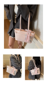 Détail du sac cabas en cuir verni rose avec ruban et pendentif cœur de style élégant