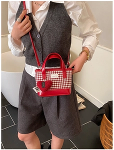 Detail of red and white checkered mini bucket bag with plush heart charm and logo