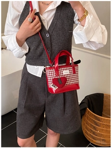 Detail of red and white checkered mini bucket bag with a heart-shaped plush charm