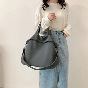 Grand sac cabas en nylon gris foncé porté par un mannequin avec bandoulière réglable chic
