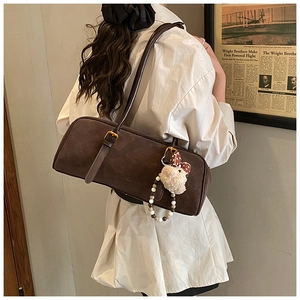 Detail view of a vintage dark brown rectangular shoulder bag with a cute plush bunny charm
