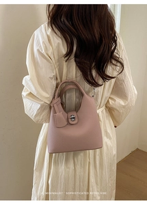 Detail of pink lychee leather bucket bag with metal twist lock and hanging charm