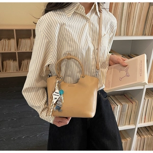 Détail du sac seau en cuir marron clair avec breloque d'ours et bandoulière réglable