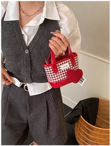 Detail of red gingham mini bucket bag with Helahe logo and red heart plush charm