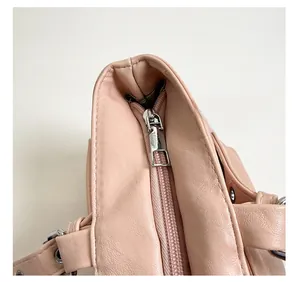 Close-up of smooth silver metal zipper on pink leather tote bag showing stitch detail