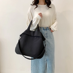 Vue détaillée du grand sac cabas en nylon noir avec bandoulière large et boucles en métal