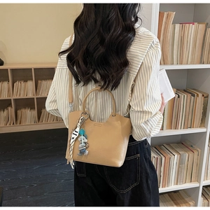 Détail du sac seau kaki avec foulard décoratif et poupée suspendus à la poignée