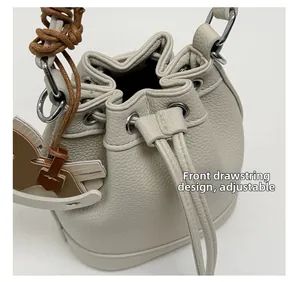 Detail view of the cream leather bucket bag showing the adjustable front drawstring design