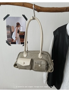 Detail of vintage canvas shoulder bag hanging on a wooden branch against a white wall
