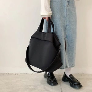 Détail d'un grand sac cabas noir en nylon montrant le design plissé et la bandoulière réglable