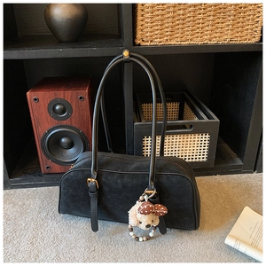 Close-up of black matte leather shoulder bag with a cute teddy bear plush charm