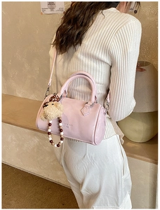 Detailed side view of pink Boston bag with fuzzy bear charm and colorful beaded strap