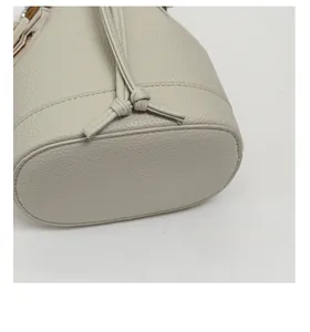Detail of reinforced bottom base on beige bucket bag showing leather texture and stitching