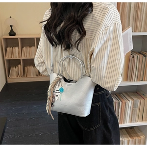Détail du sac cabas argenté avec poignées rondes et breloques de mode mignonnes