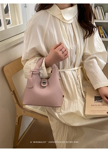 Detail of light pink lychee leather handbag with silver clasp on a textured dress background