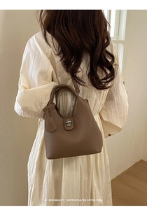 Brown leather bucket bag with silver twist lock and lychee texture shown on model