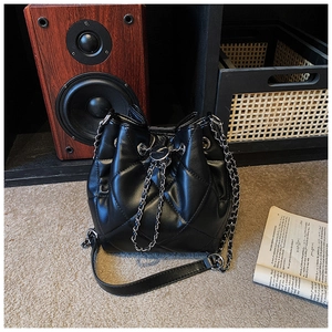 Detailed macro shot of black quilted pattern bucket bag with drawstring and chain strap