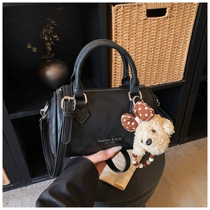 Close-up of black matte Boston bag with Fashion & Bag text and cute teddy bear charm