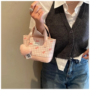 Detailed close-up of pink plaid mini bucket bag with bow print and heart plush pendant