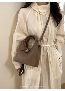Close-up of vintage brown leather bucket bag with silver buckle and crossbody strap
