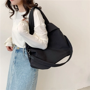 Grand sac fourre-tout minimaliste en nylon noir avec bandoulière porté par un mannequin