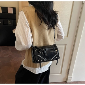 Detail of black bowling bag with silver zipper accents worn as a crossbody by a model