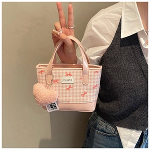 Detailed view of pink plaid bucket bag featuring bow accents and plush heart charm