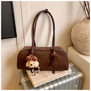 Detailed macro view of vintage brown matte leather shoulder bag with cute dog pendant accessory