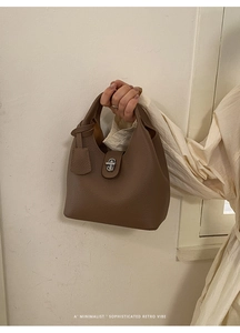 Detail of a brown lychee-patterned leather bucket bag with silver metal swivel clasp