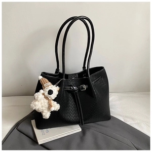 Detail of black woven tote bag featuring a cute white teddy bear plush charm