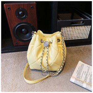 Detail of light yellow quilted bucket bag with silver chain and metal buckle decoration