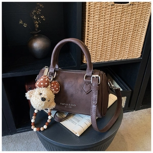 Detailed view of vintage coffee Boston bag with plush bear charm and metallic logo