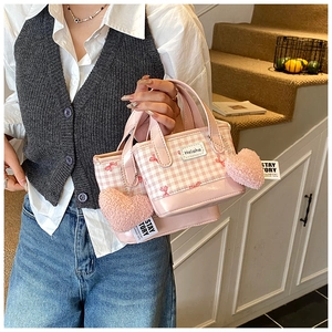 Detail of pink plaid handbag with cute heart plush charms and small red bow accents