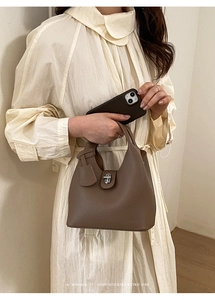Detailed view of brown lychee grain leather bucket bag with silver twist lock and hangtag